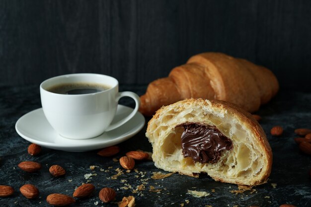 Concepto de sabroso desayuno con croissant con chocolate en la oscuridad