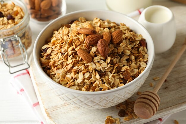 Concepto de sabroso desayuno con granola sobre fondo blanco de madera