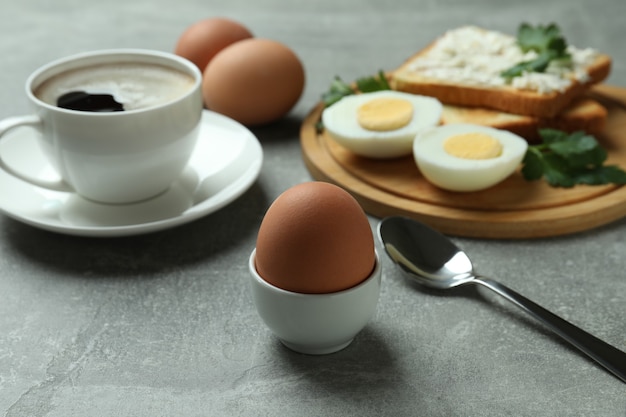 Concepto de sabroso desayuno con huevos duros en mesa con textura gris