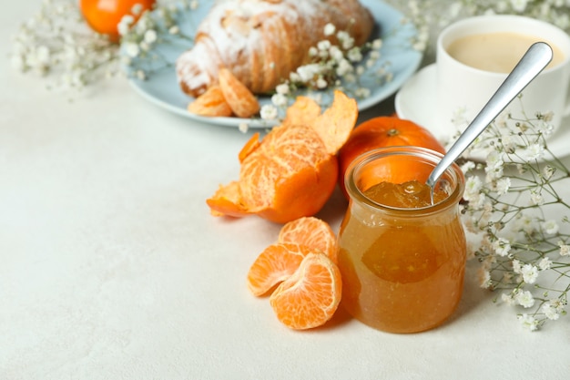 Concepto de sabroso desayuno con mermelada de mandarina en mesa con textura blanca