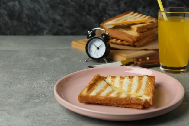 Concepto de sabroso desayuno con sándwich a la parrilla en mesa con textura gris