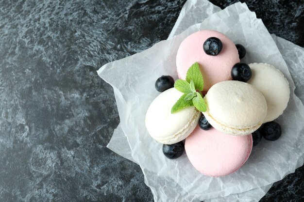 Concepto de sabroso postre con macarrones sobre fondo negro ahumado