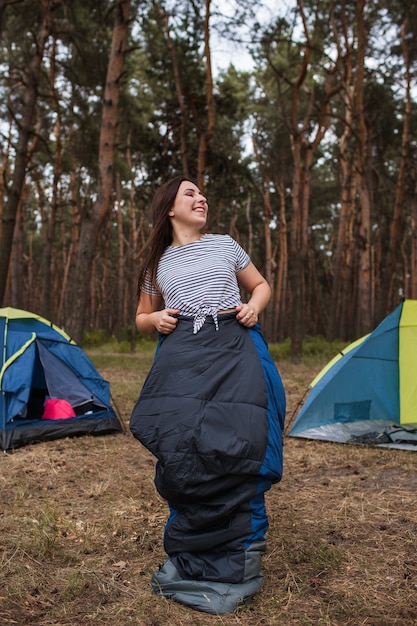 Concepto de saco de dormir turístico confortable mujer feliz. Anuncio de equipos de senderismo.