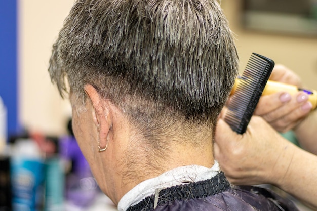 concepto de salón de belleza y corte de pelo estilista cortando el cabello gris de las mujeres mayores manos femeninas sostienen