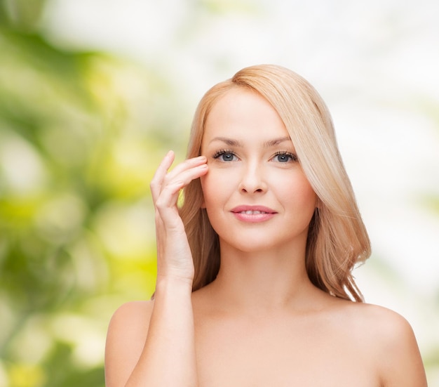 concepto de salud y belleza - cara de mujer hermosa tocando su área de los ojos