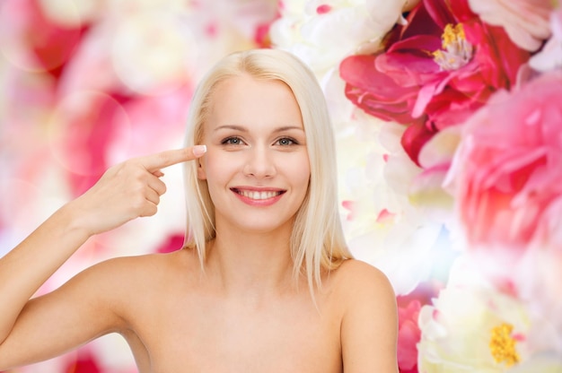 concepto de salud y belleza - cara de mujer hermosa tocando su área de los ojos