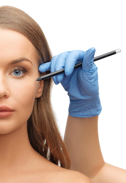 Foto concepto de salud, belleza y cirugía plástica - rostro de mujer y manos de esteticista con lápiz