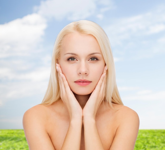 concepto de salud y belleza - hermosa mujer tocando la piel de su cara