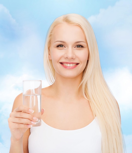 concepto de salud y belleza - joven mujer sonriente con un vaso de agua