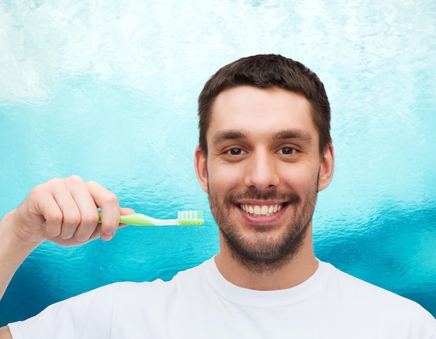 concepto de salud y belleza - joven sonriente con cepillo de dientes