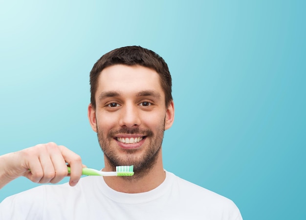 concepto de salud y belleza - joven sonriente con cepillo de dientes