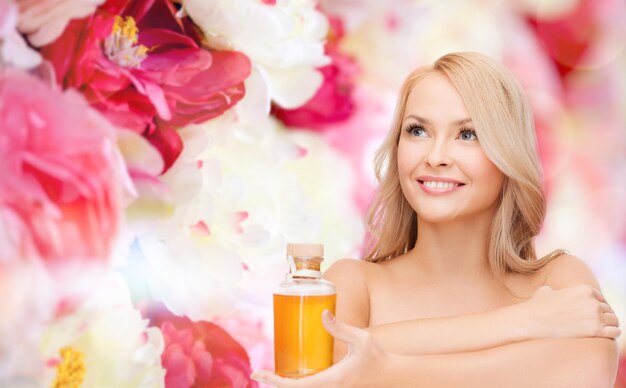 concepto de salud y belleza - mujer feliz con botella de aceite