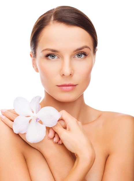 concepto de salud y belleza - mujer relajada con flor de orhid