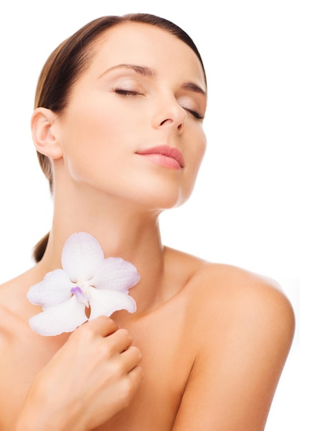 concepto de salud y belleza - mujer relajada con flor de orhid