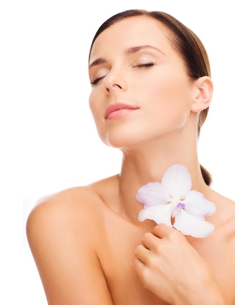 concepto de salud y belleza - mujer relajada con flor de orhid