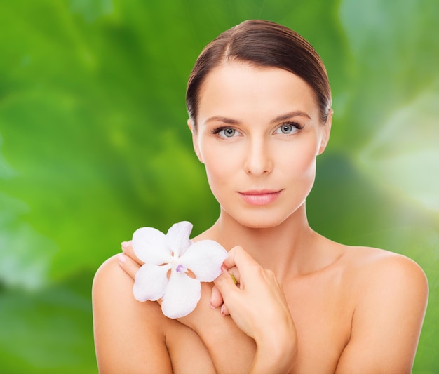 concepto de salud y belleza - mujer relajada con flor de orquídea