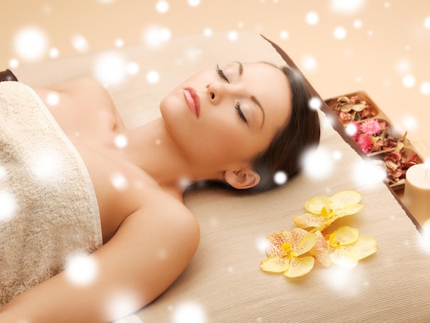 Concepto de salud y belleza - mujer en el salón de spa acostado en la mesa de masajes