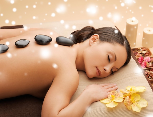 concepto de salud y belleza - mujer en el salón de spa con piedras calientes