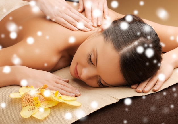 Concepto de salud y belleza - mujer en el salón de spa recibiendo masajes