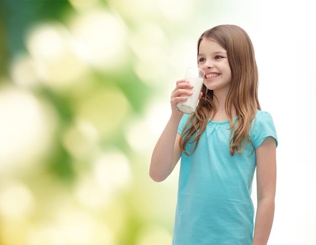 concepto de salud y belleza - niña sonriente bebiendo leche de vidrio