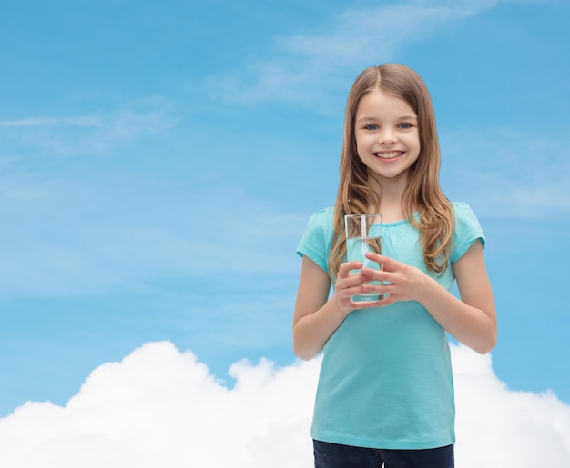 concepto de salud y belleza - niña sonriente con un vaso de agua
