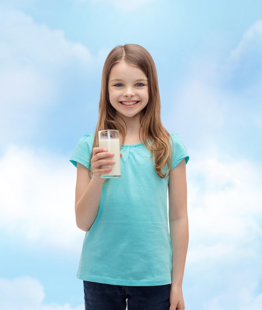 concepto de salud y belleza - niña sonriente con un vaso de leche