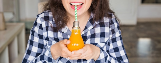 Concepto de salud, comida, dieta y personas: mujer joven bebiendo jugo natural en una botella y parece ser sabroso.