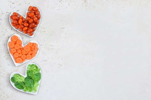 Concepto de salud del corazón Verduras en placas en forma de corazón sobre fondo de piedra con espacio de copia