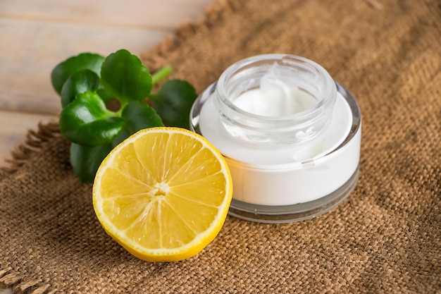 Concepto de salud. Cosmética ecológica con limón. Crema hidratante natural sobre un fondo de madera.