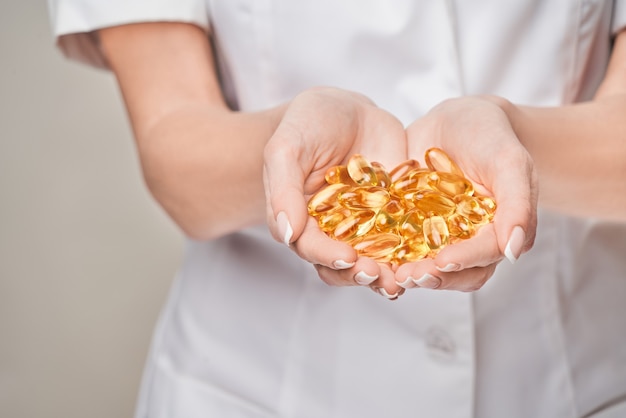 Concepto de salud y dieta: médico nutricionista o cardiólogo con aceite de pescado en cápsulas de vitamina D y ácidos grasos omega-3