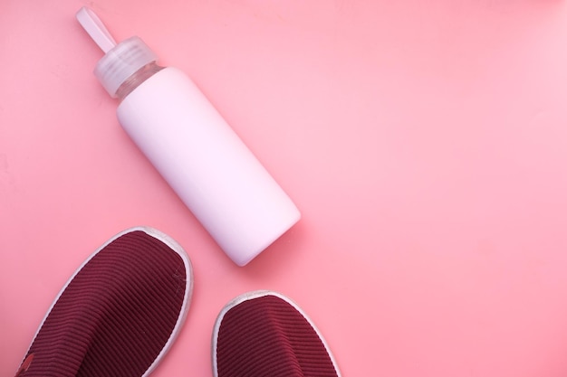 Concepto de salud y fitness con zapato y botella de agua sobre fondo rosa