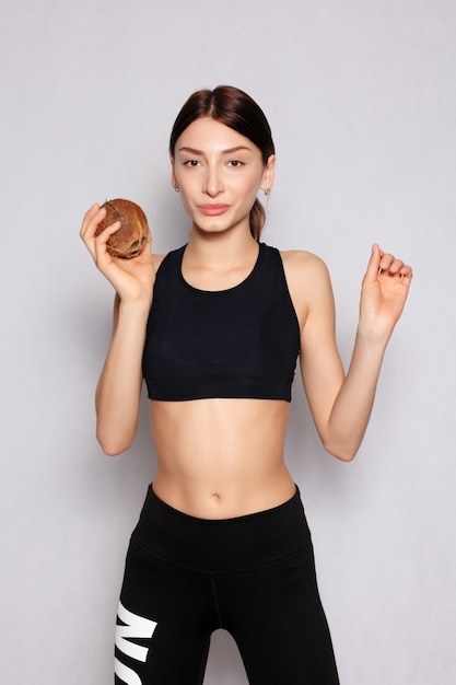 Concepto de salud, gente, comida y belleza: hermosa joven con un maquillaje natural ligero y una piel perfecta con coco en la mano. Rostro de belleza. Fotografía tomada en el estudio sobre un fondo blanco.