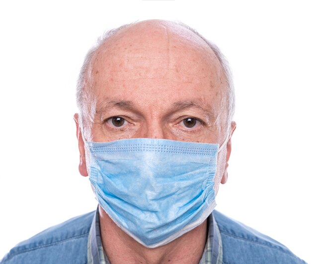 Concepto de salud. Hombre senior en máscara protectora posando en estudio sobre fondo blanco.