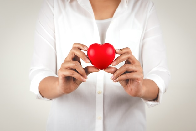 Concepto de salud de la mano de mujer joven con corazón rojo