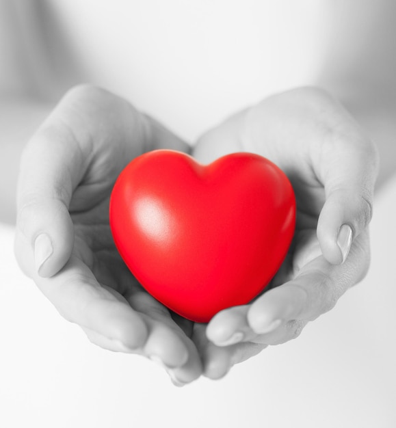 concepto de salud, medicina y caridad - cierre de manos femeninas con un pequeño corazón rojo