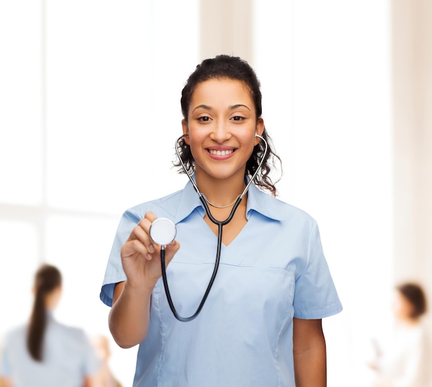 concepto de salud y medicina - doctora o enfermera afroamericana sonriente con estetoscopio