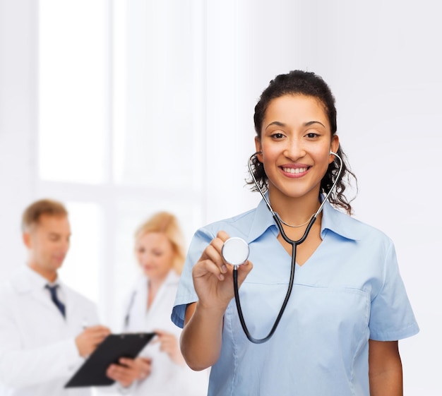 concepto de salud y medicina - doctora o enfermera afroamericana sonriente con estetoscopio