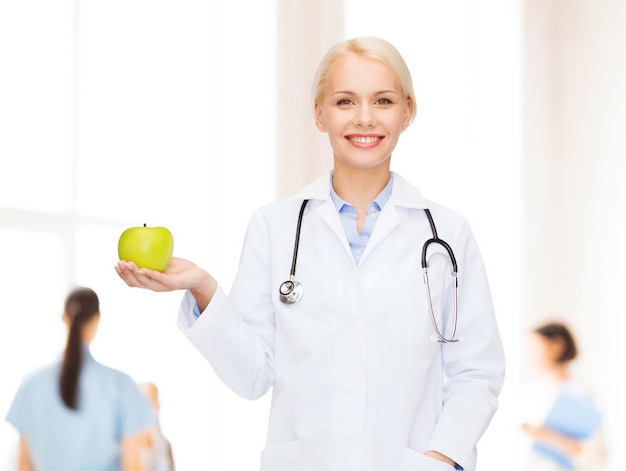 concepto de salud y medicina - doctora sonriente con estetoscopio y manzana verde