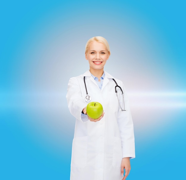 concepto de salud y medicina - doctora sonriente con estetoscopio y manzana verde