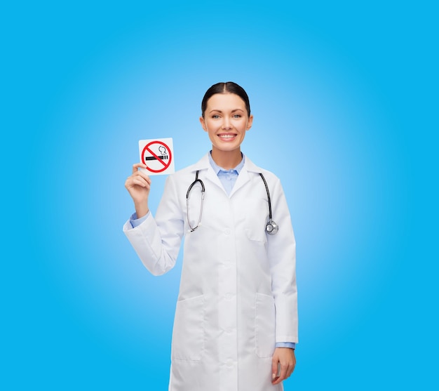 concepto de salud y medicina - doctora sonriente con estetoscopio sosteniendo un cartel de no fumar
