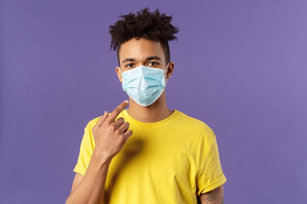 concepto de salud y medicina. Joven hispano con corte de pelo afro, uso y punta de máscara facial, distanciamiento social durante una pandemia, explica a tus amigos cómo prevenir la enfermedad