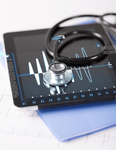 concepto de salud, medicina y tecnología - tablet pc, estetoscopio y electrocardiograma