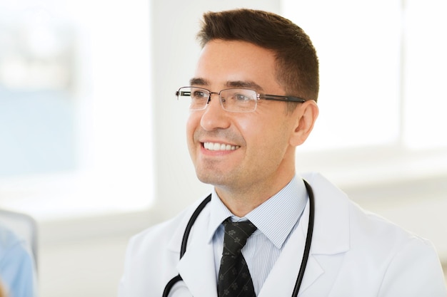 concepto de salud, profesión y medicina - médico sonriente con bata blanca y anteojos en el hospital