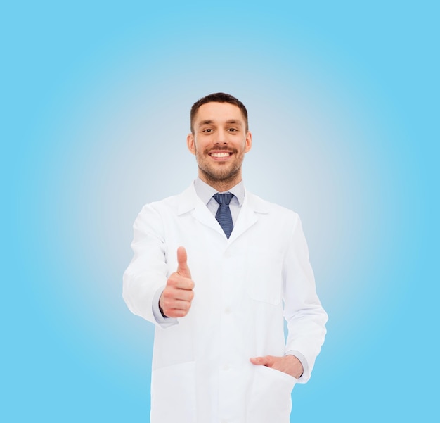 El concepto de salud, profesión y medicina: un médico sonriente que muestra los pulgares hacia arriba sobre el fondo blanco