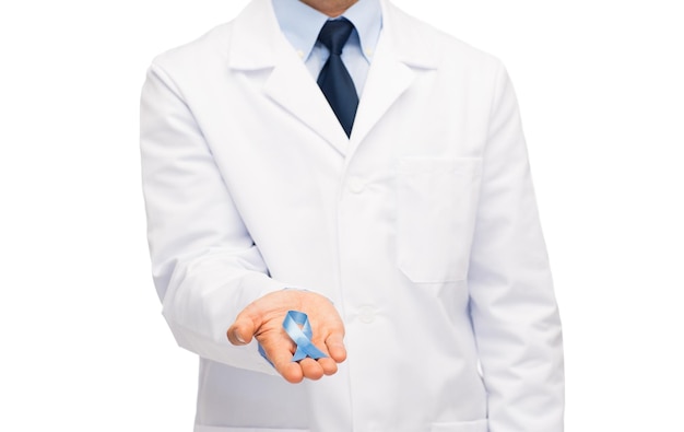 concepto de salud, profesión, personas y medicina - cierre de un médico varón con bata blanca que sostiene una cinta de concientización sobre el cáncer de próstata azul cielo