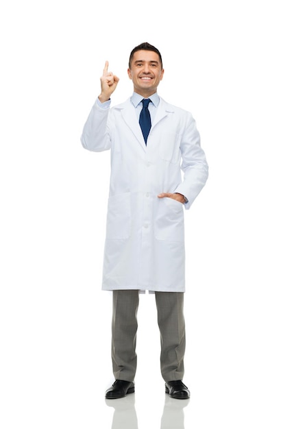 concepto de salud, profesión, personas y medicina - médico sonriente con bata blanca señalando con el dedo