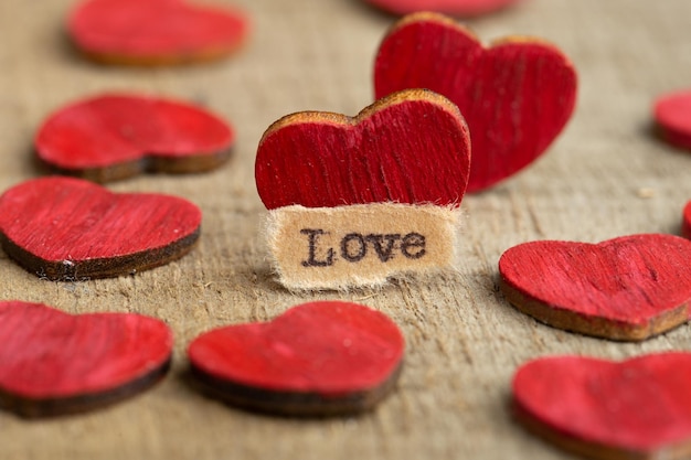 Concepto de saludos del Día de San Valentín Pequeño corazón de madera rojo y texto Amor cerca de la tarjeta de felicitación de San Valentín