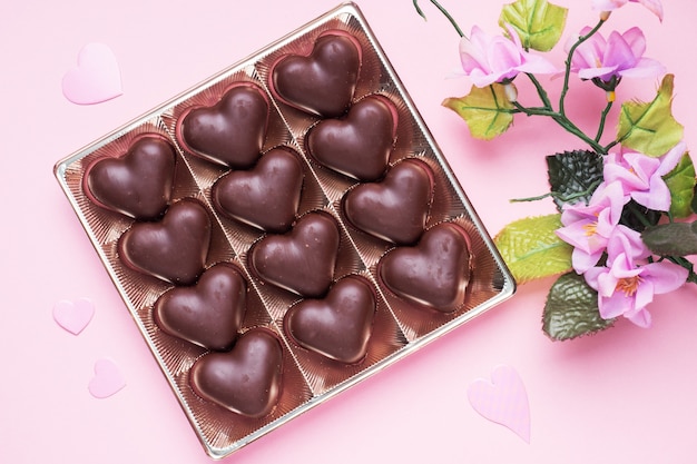 Concepto de San Valentín. Caramelos de chocolate, corazones sobre un fondo rosa