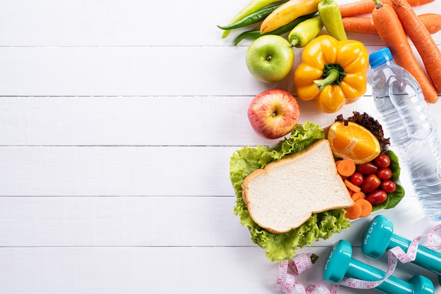 Concepto sano de la forma de vida, de la comida y del deporte en el fondo de madera blanco.