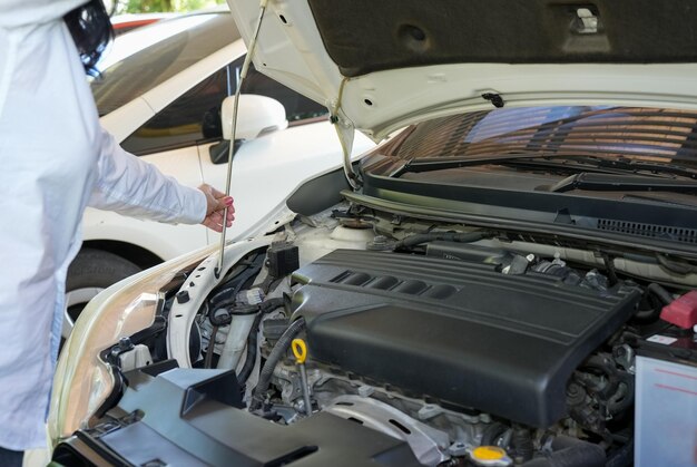 Concepto de seguridad del vehículo Mano de mujer comprobando el motor del coche antes de conducir